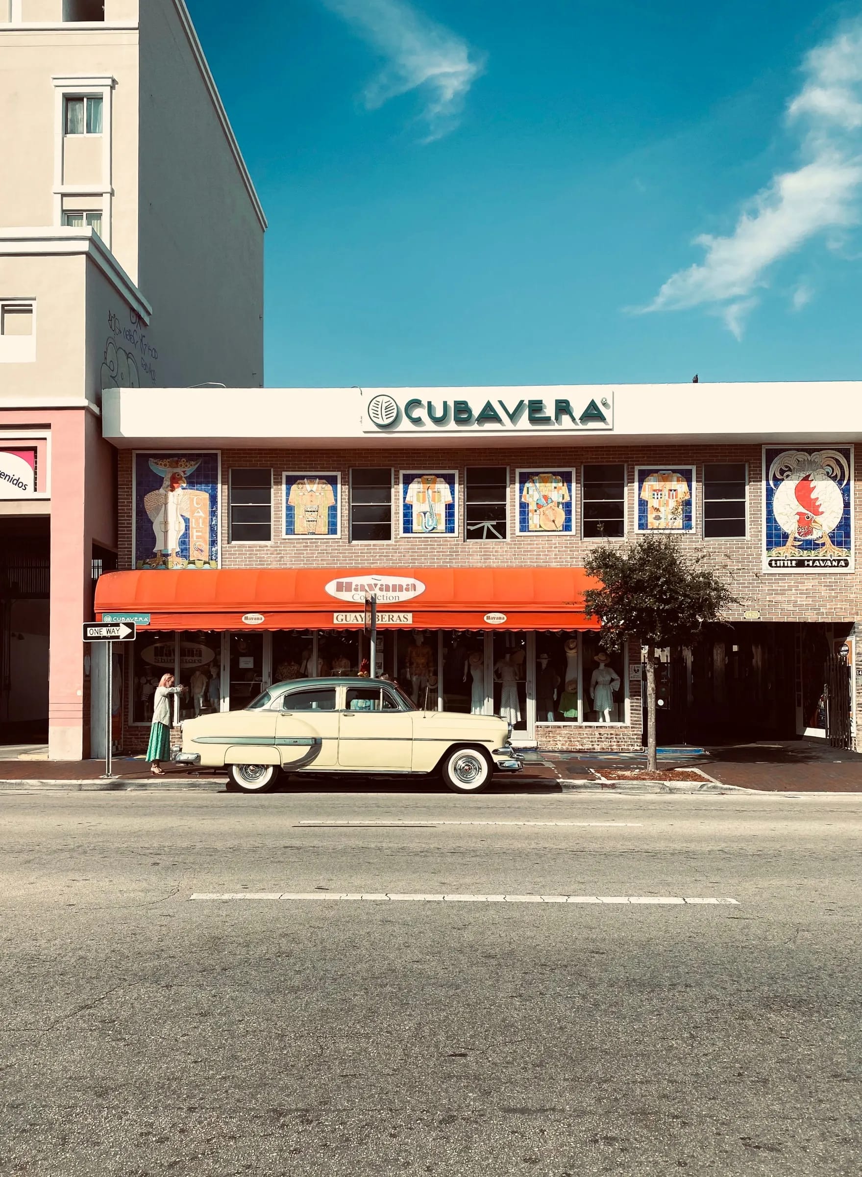 Coche antiguo color crema frente a una tienda en Little Havana