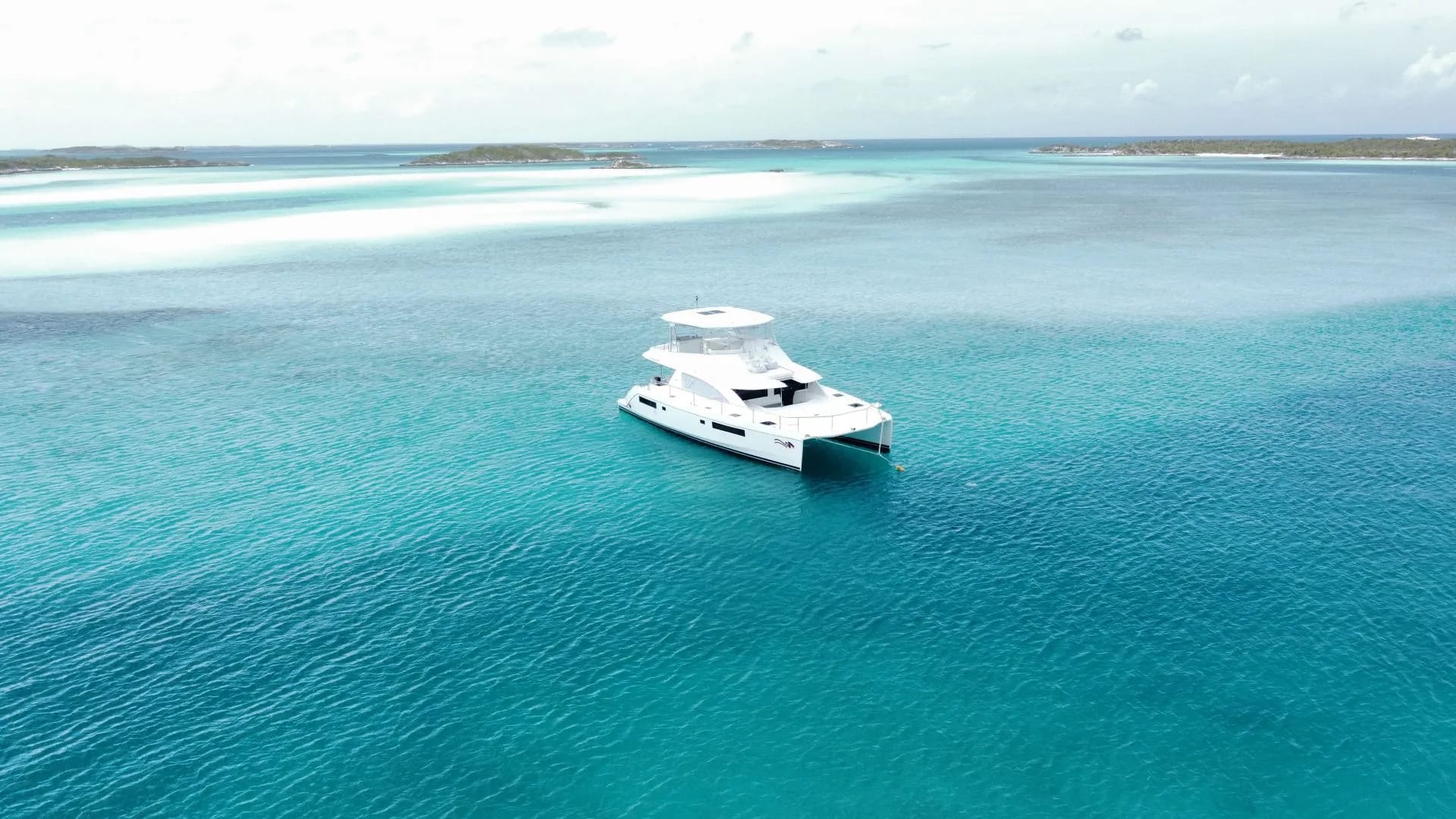 Catamaran at anchor above pale sandbars