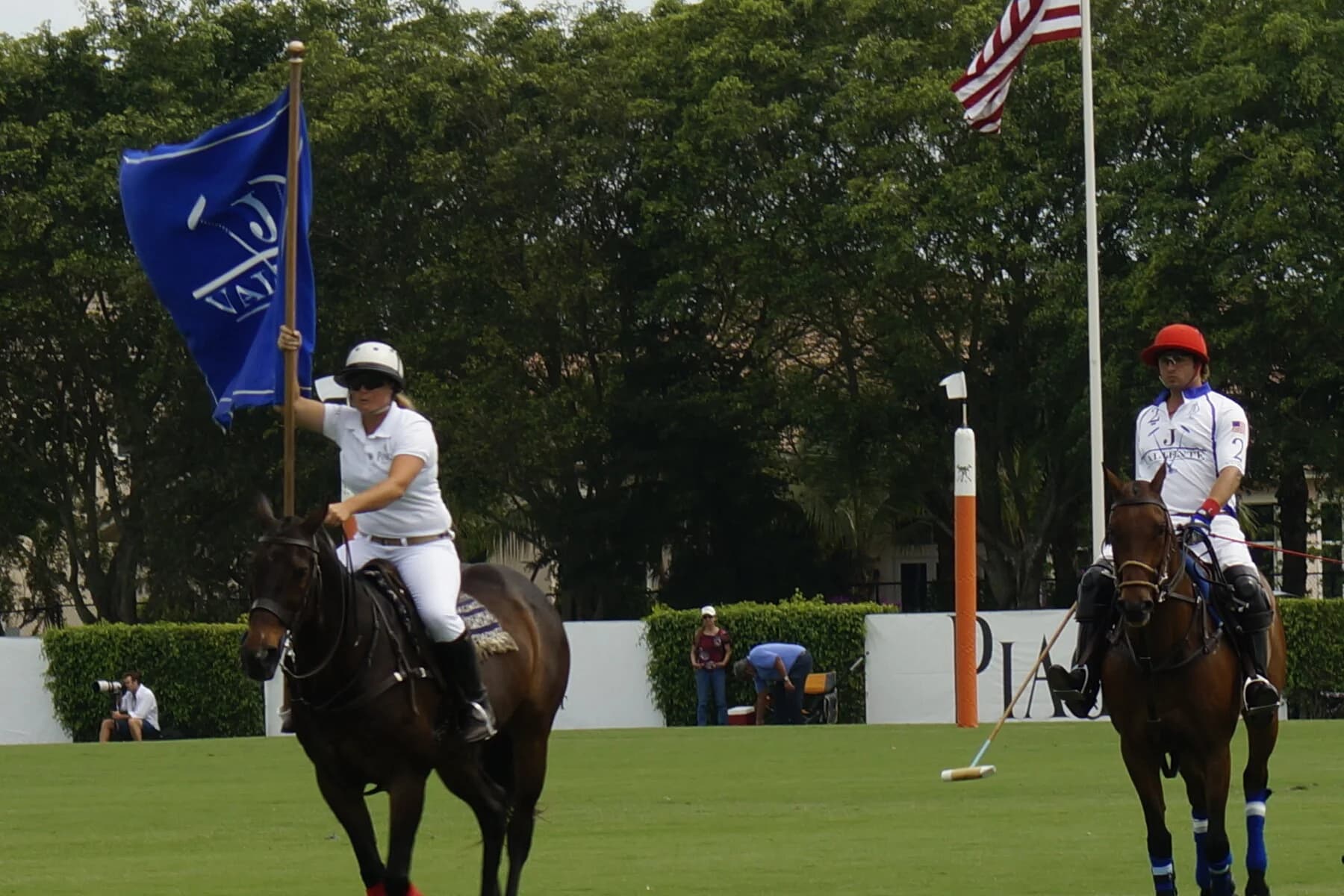 Polo players on horseback with a flag on the field in Wellington
