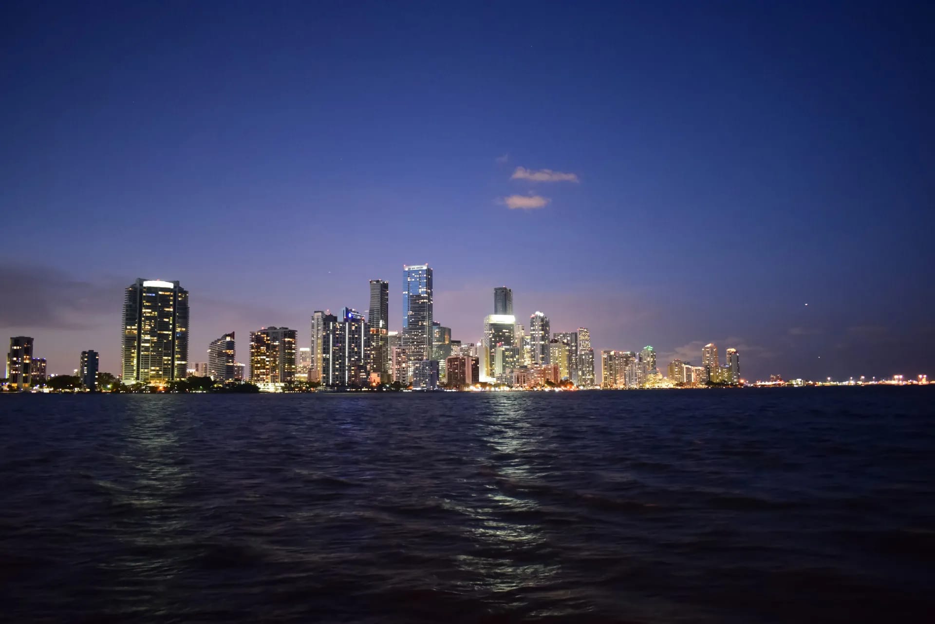 Skyline von Miami bei Nacht über dem dunklen Wasser der Biscayne Bay