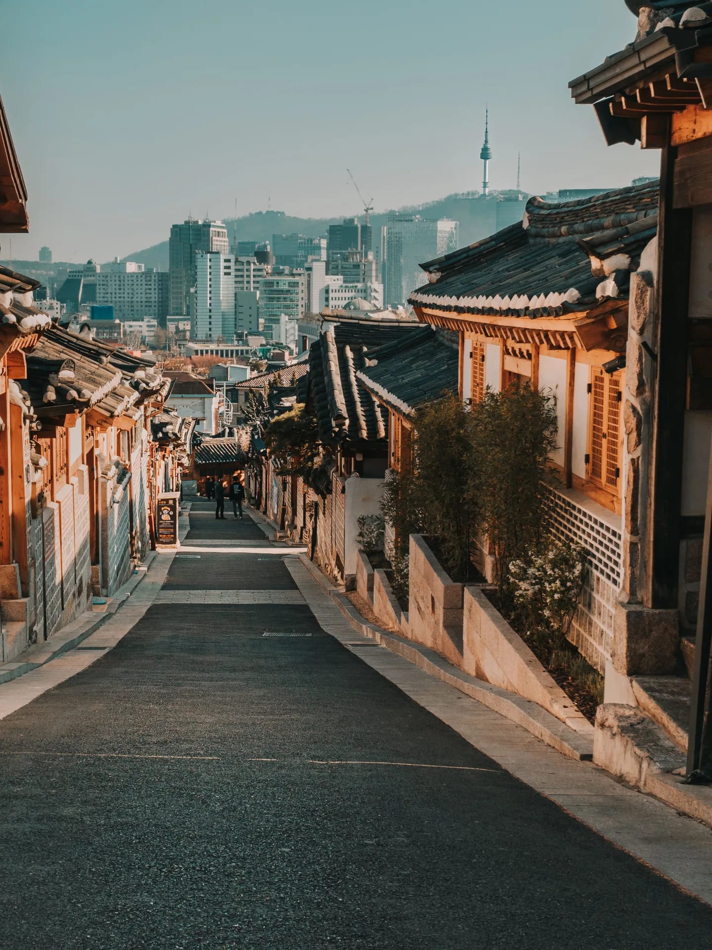 A hanok lane in Bukchon with the Seoul skyline behind